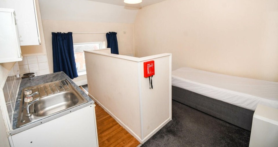 The flat boasts a kitchen, shower, single bed, a small cupboard, a mirror and a fridge