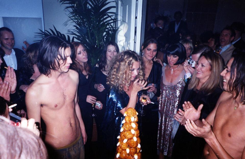 Kate with a cig and a drink as topless hunks cheer her on at the party