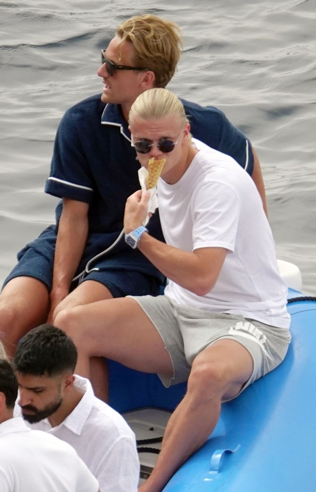 a man sitting on a boat eating an ice cream cone