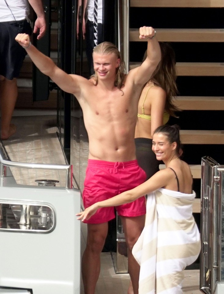 a shirtless man in pink shorts stands next to a woman wrapped in a towel