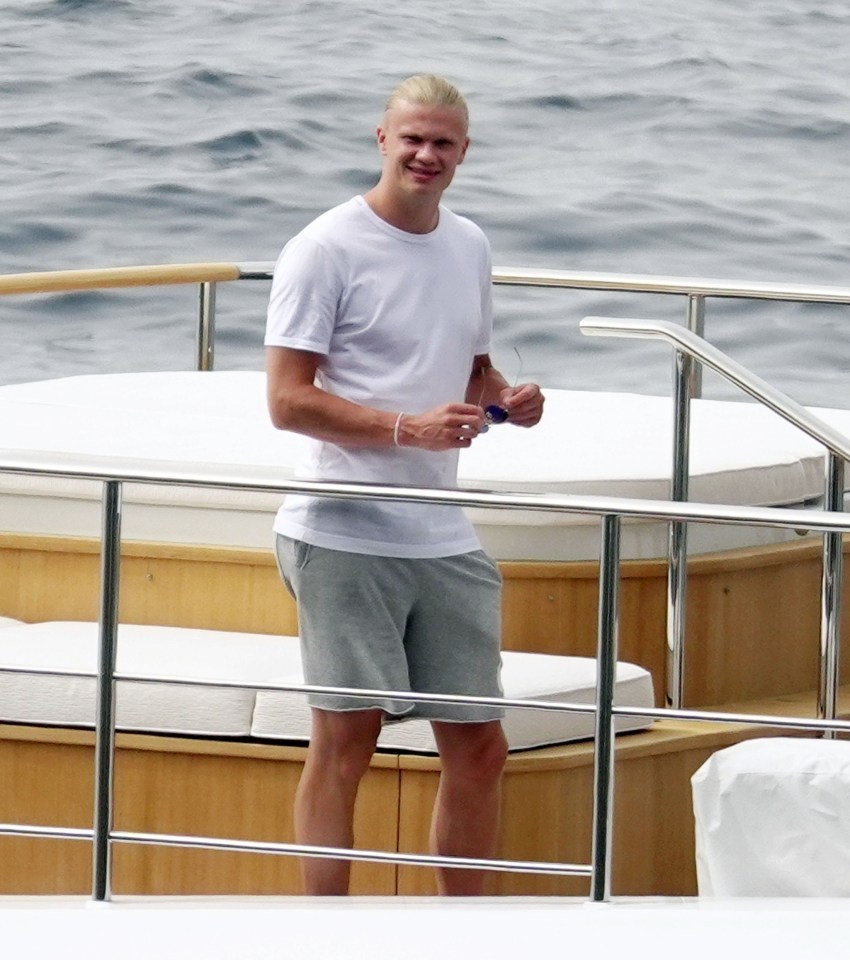 a man in a white shirt and grey shorts is standing on a boat