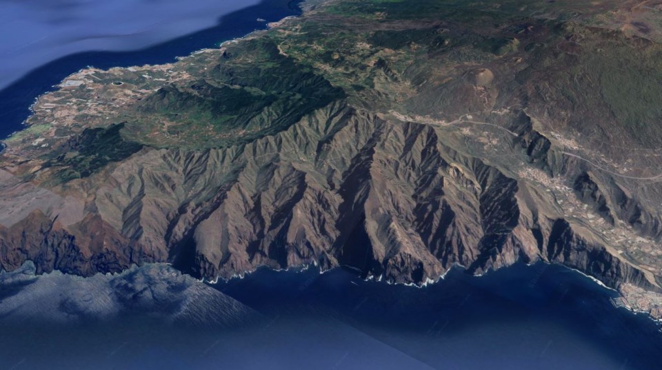 an aerial view of a mountain range near the ocean