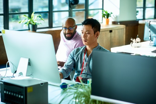 two men are looking at a computer screen in an office