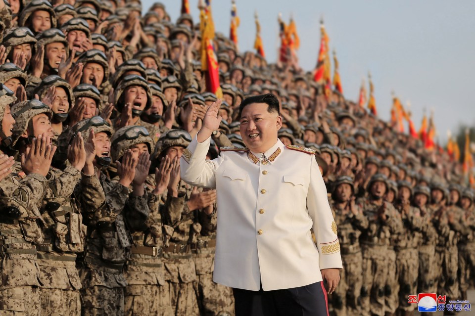 a man in a white uniform stands in front of a crowd of soldiers