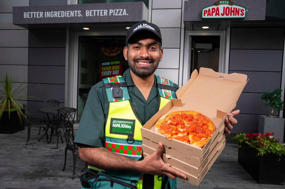 a man in a papa john 's uniform holds a box of pizza