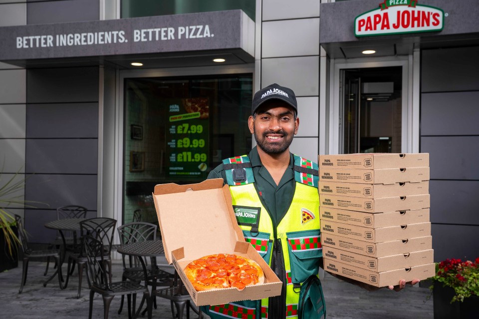 a man in a papa john 's uniform holds a box of pizza