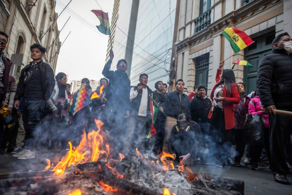 People wave Bolivia’s national flag as they yell at the military police during a coup attempt