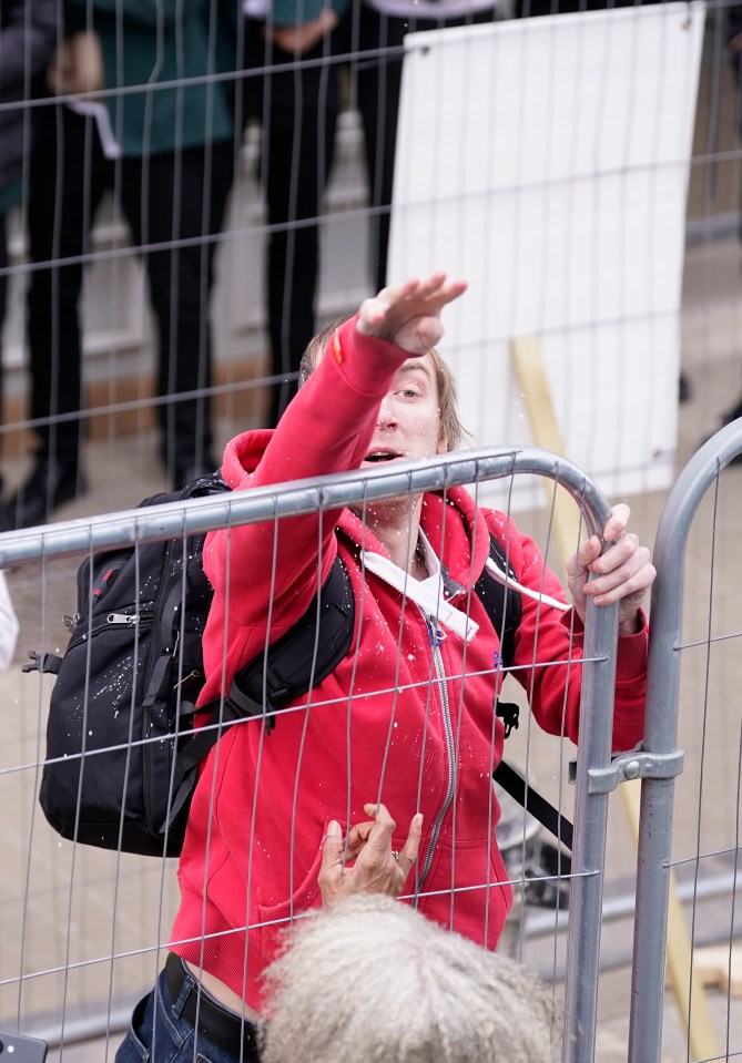 The yob was pictured appearing to throw wet cement at Farage