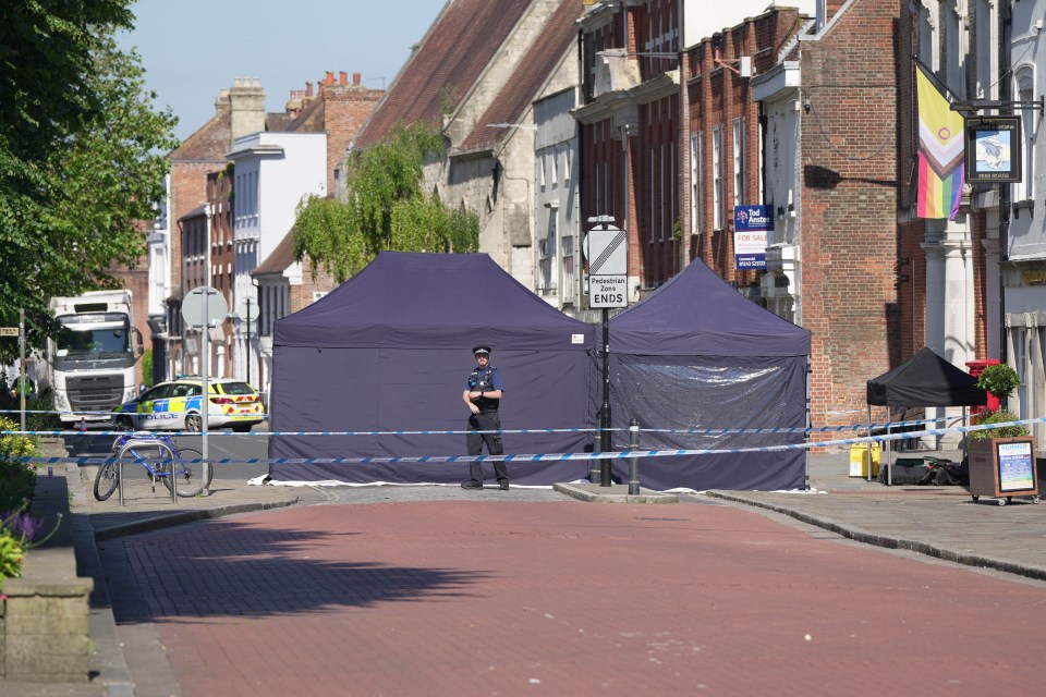 a police officer stands in front of a blue tent with a sign that says ' no entry ' on it