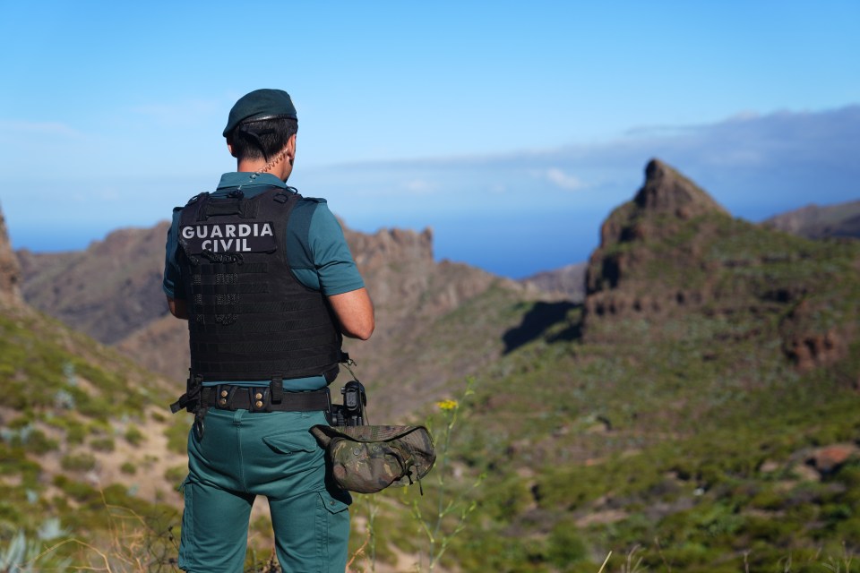 a man in a guardia civil vest stands in front of a mountain