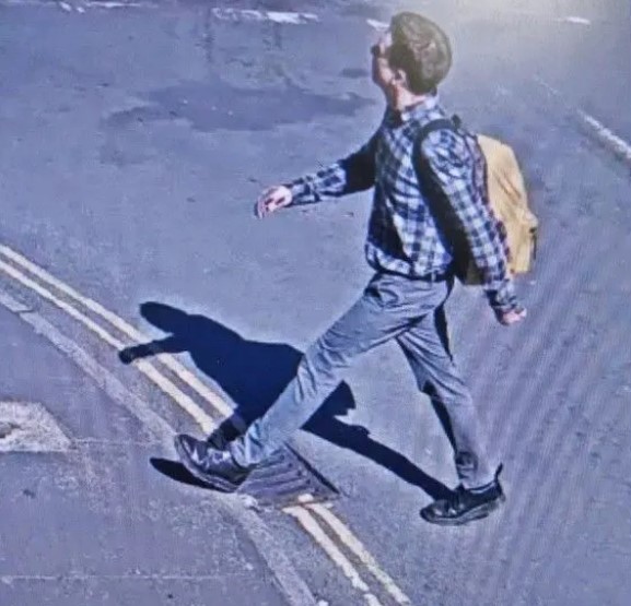 a man with a backpack is walking across a street .