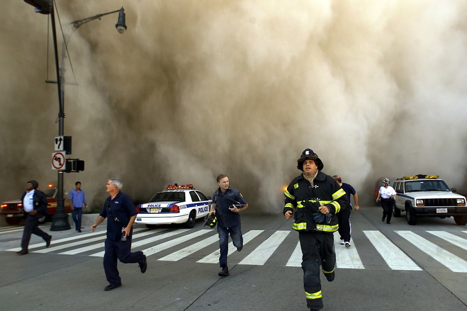 Police and firemen run away from the huge dust cloud caused as the World Trade Center’s Tower One collapses on September 11 2001