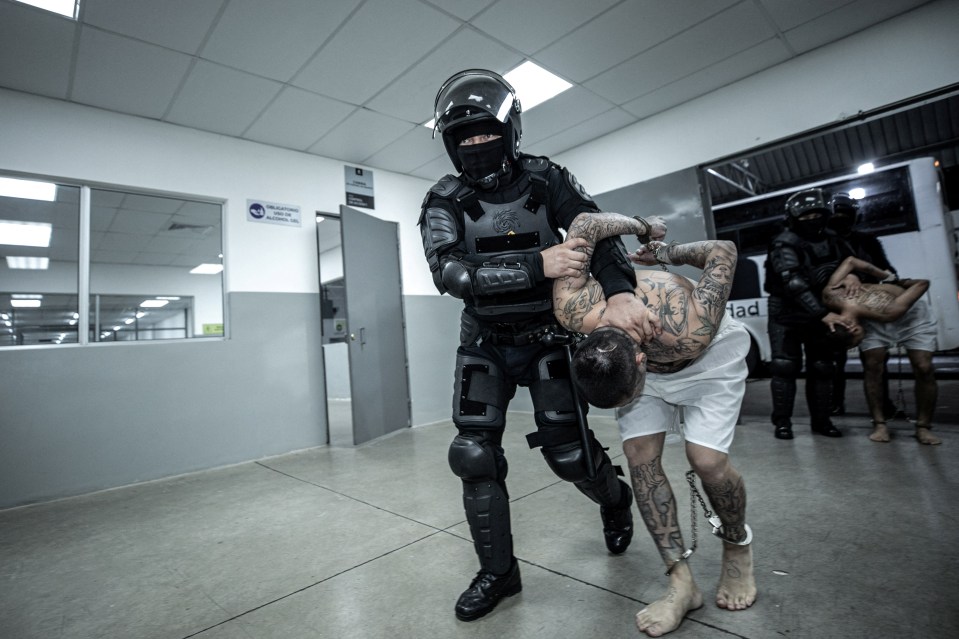 Prison guards lead inmates for processing at the new facility in El Salvador