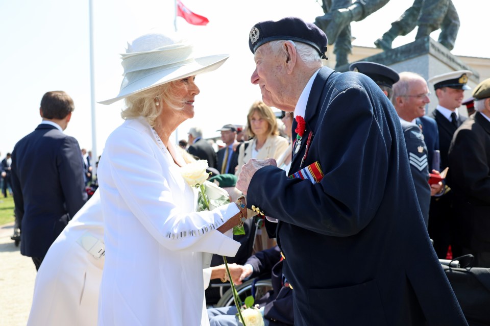 Queen Camilla receives a white rose from a veteran