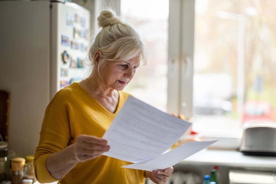 a woman in a yellow sweater is reading a piece of paper