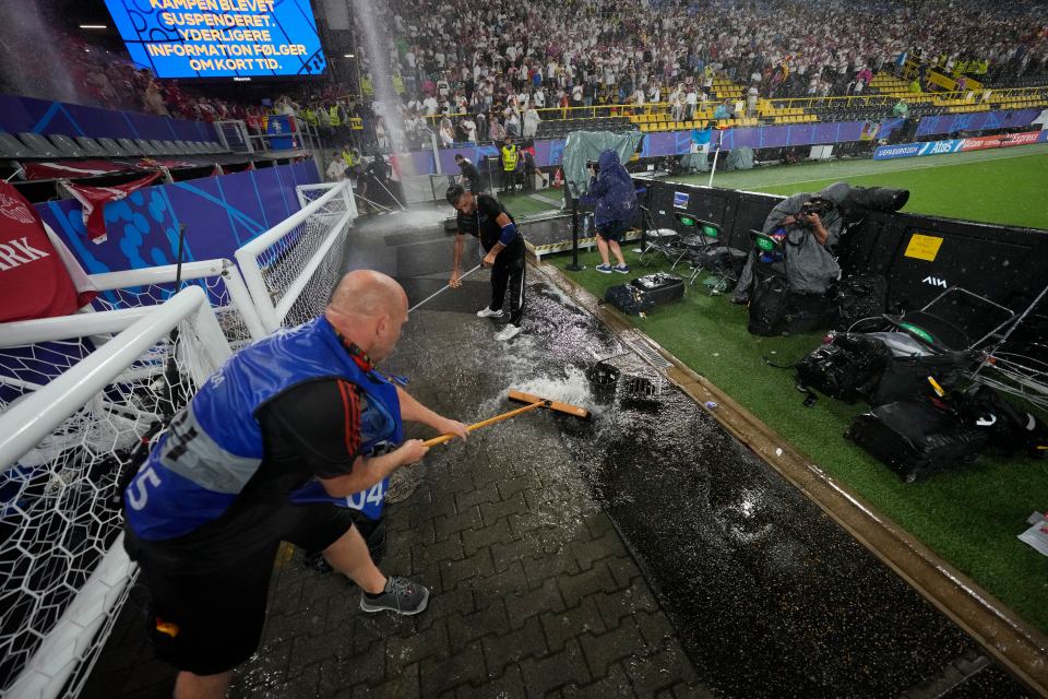 Stadium staff swept water off the sidelines