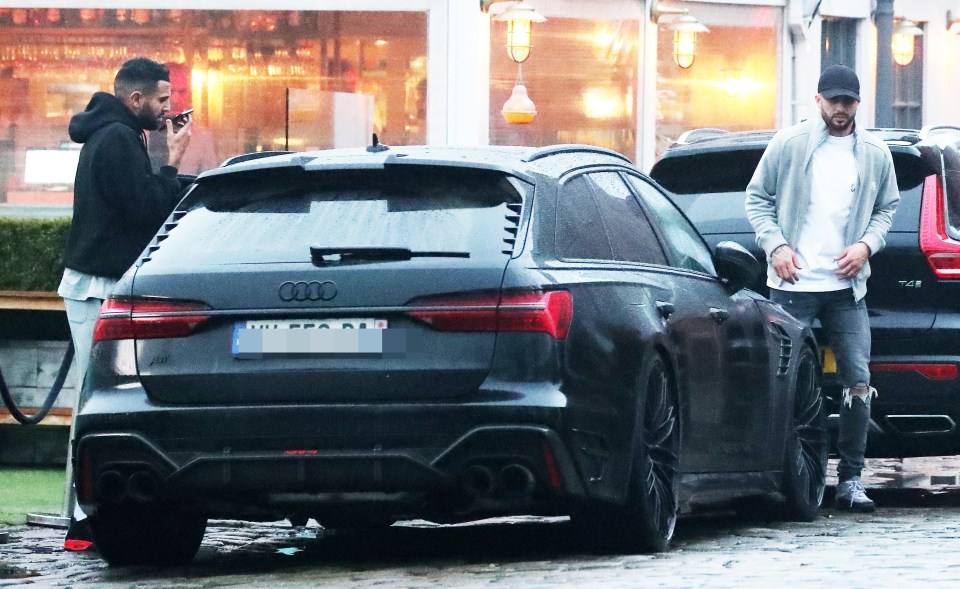 a man talking on a cell phone next to an audi