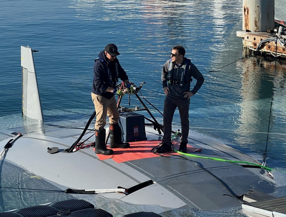 DARPA program manager Dr Kyle Woerner (right) talks with a member of the Northrop Grumman team while standing atop the Manta Ray