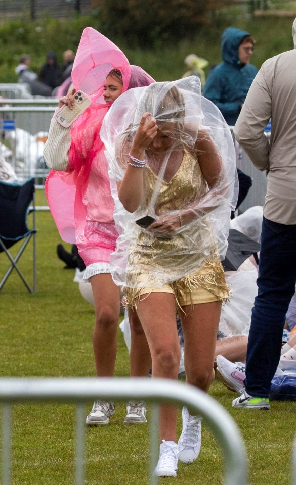 A fan shelters under a plastic poncho as she waits for Taylor to take to the stage