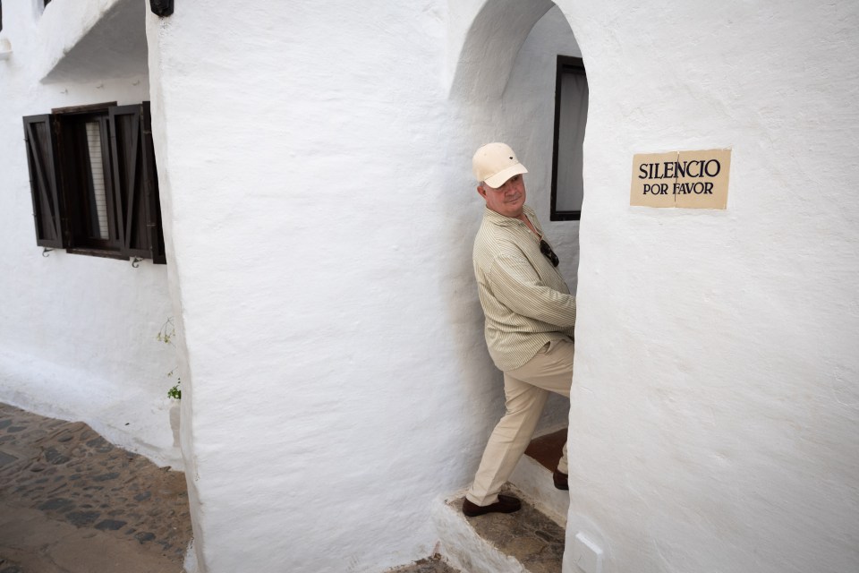 A tourist walks past a sign reading “Silence please”