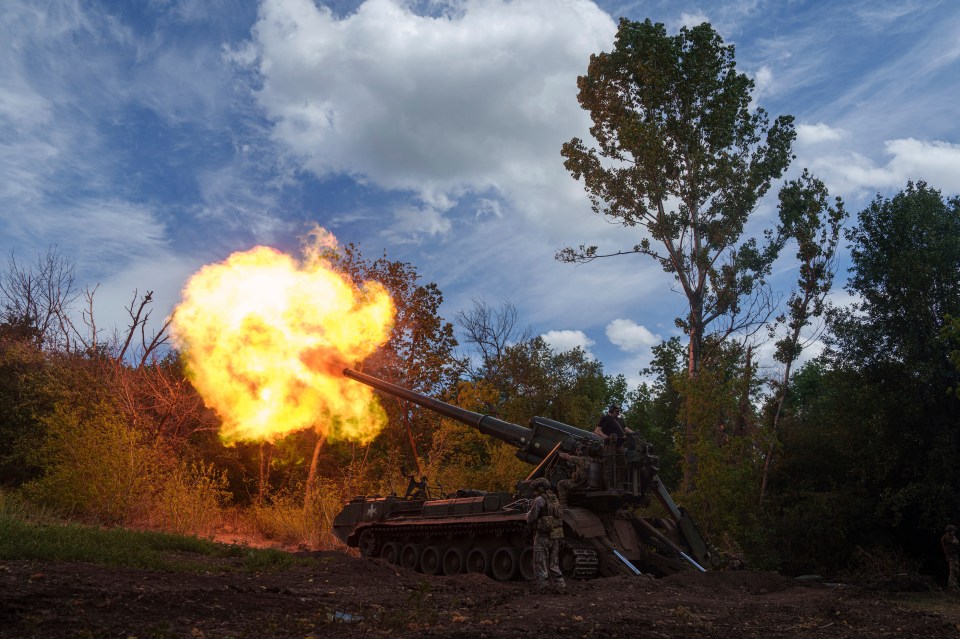 a military vehicle is firing a cannon with flames coming out of it