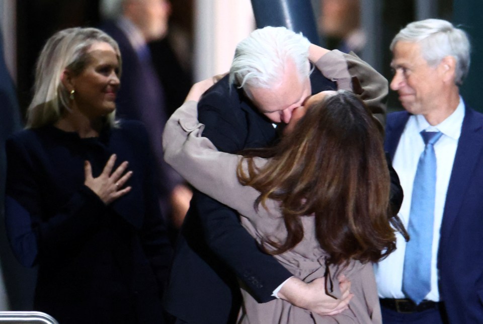 a man in a suit kisses a woman on the cheek