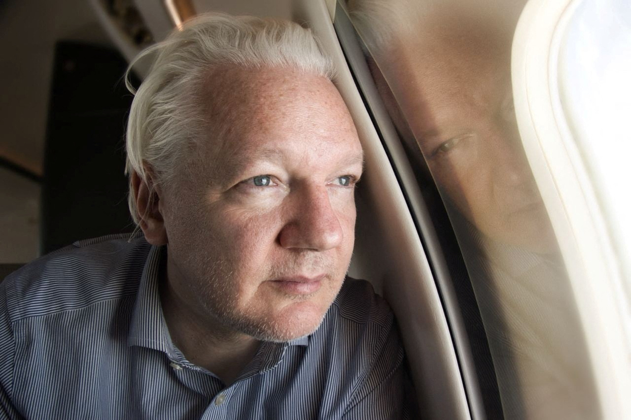 Assange, 52, looks out the window as his plane lands in Bangkok on Tuesday