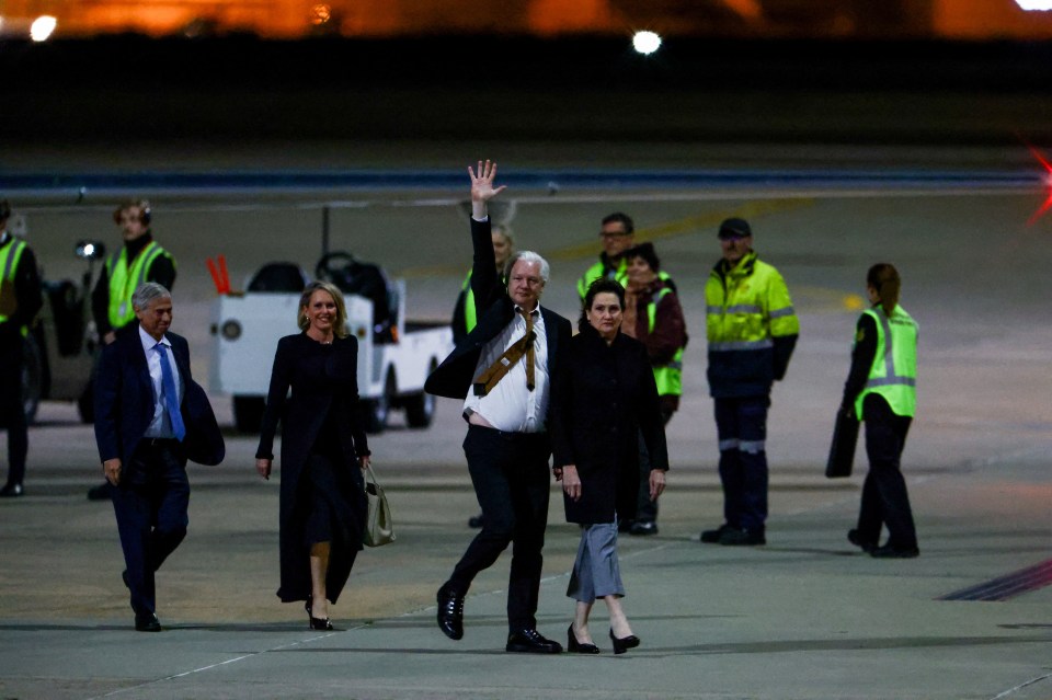 a man in a suit and tie is waving at the camera