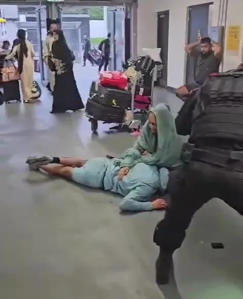 A woman wearing a headscarf knelt next to the teen after he was kicked in the head