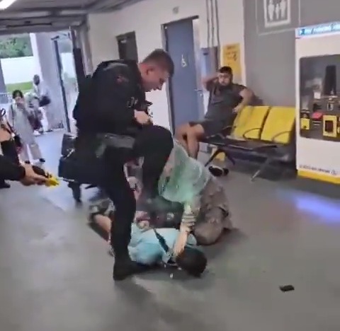 The police officer rose his foot above the man's head