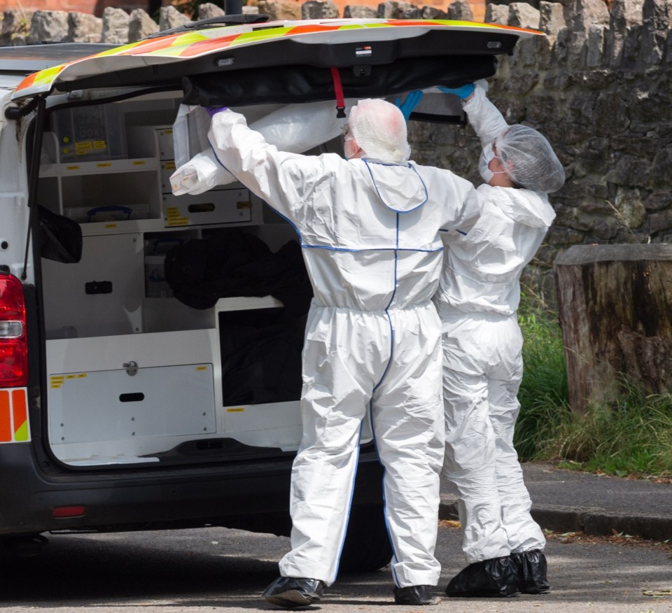 a man in a white suit is loading something into the back of a police van