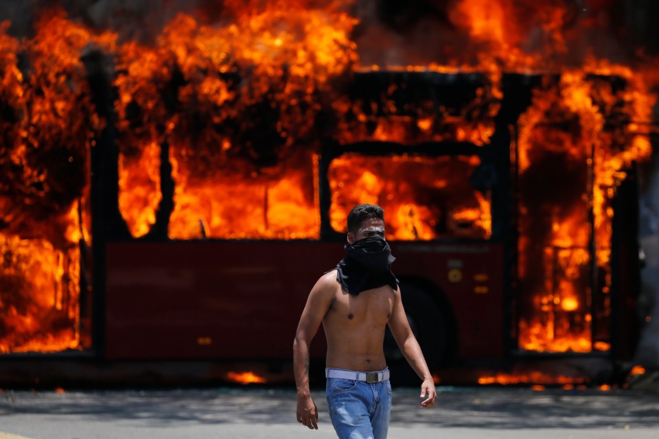 An anti-government protester walks near a bus that was set on fire by protesters in 2019