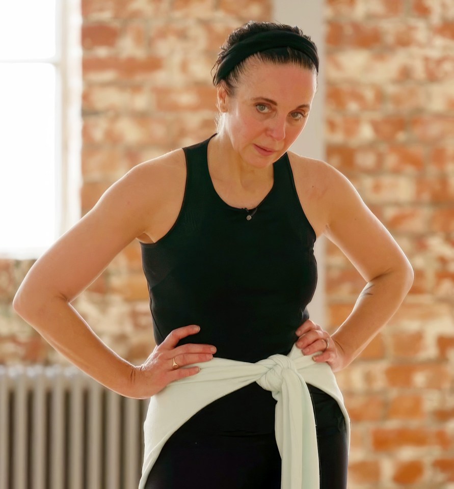 a woman in a black tank top stands with her hands on her hips