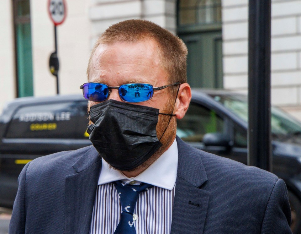 a man wearing sunglasses and a face mask stands in front of a redson lee van