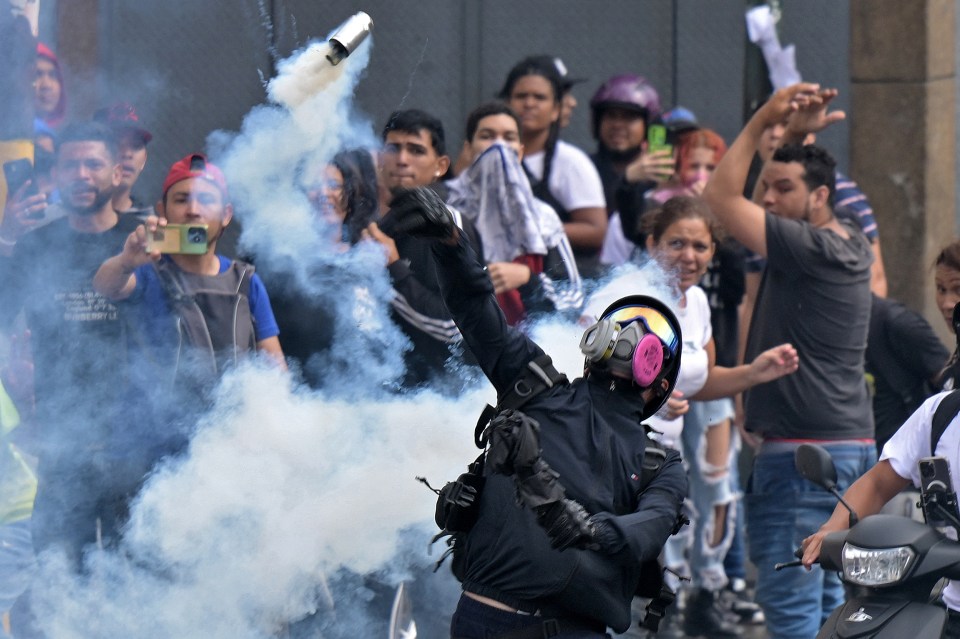 A protester returns a tear gas canister back at police