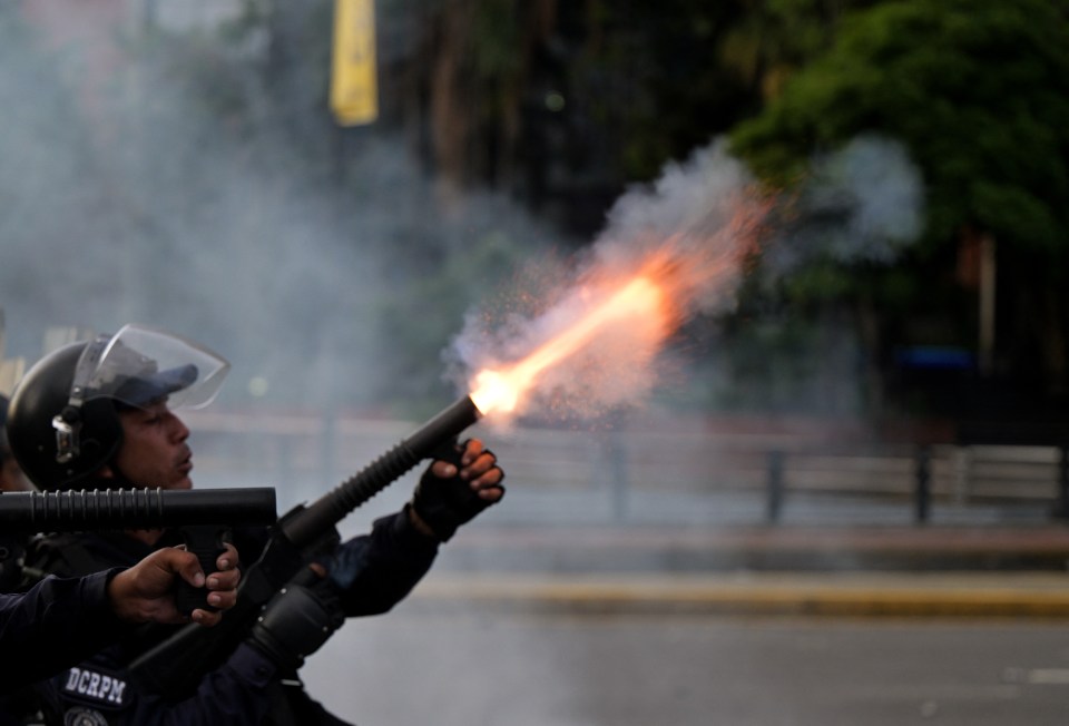 A police officer fires tear gas