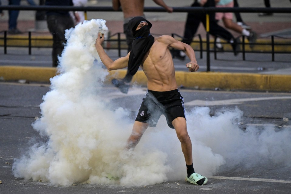 A demonstrator returns a teargas canister at police