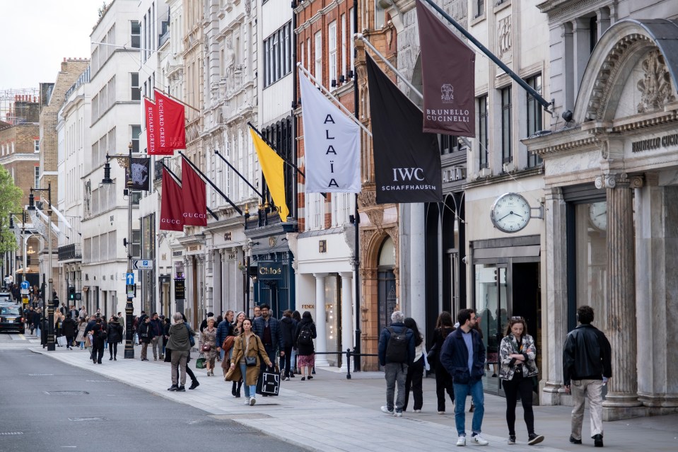 a group of people walking down a street with a iwc schaffhausen store in the background