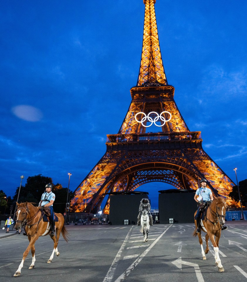 two police officers are riding horses in front of the eiffel tower