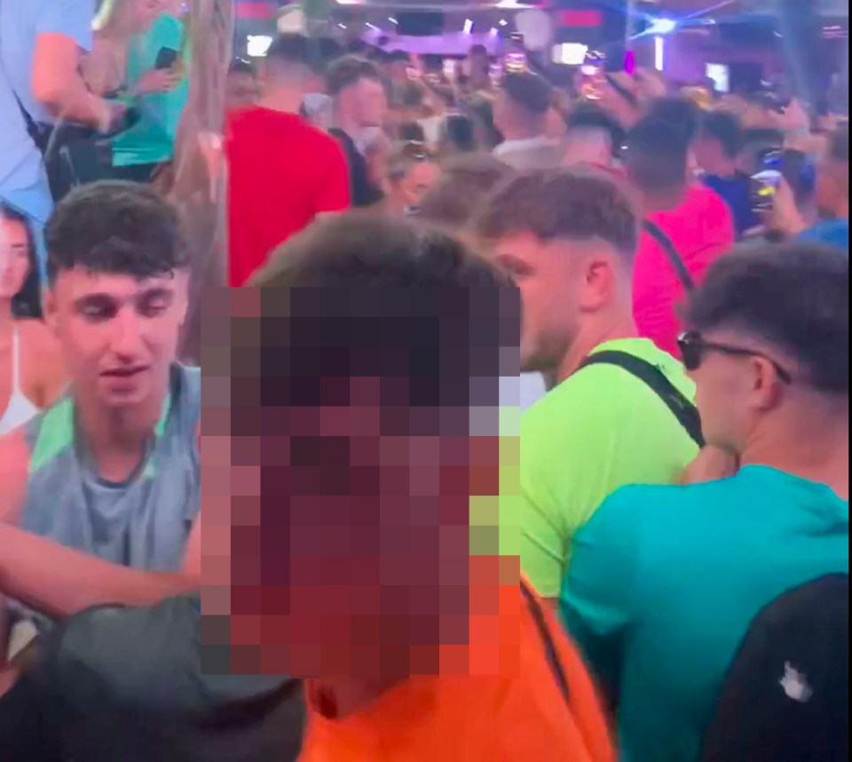 a blurry picture of a crowd of people including a man in an orange shirt