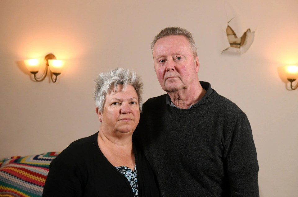 Mark and Chrissie Bacon in front of a hole in the wall created by Martin