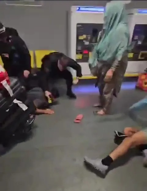 a group of people are standing around a man laying on the floor .