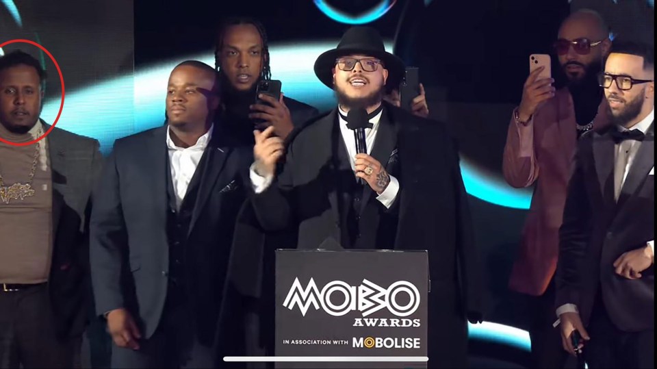 a group of men standing around a podium that says mobo awards