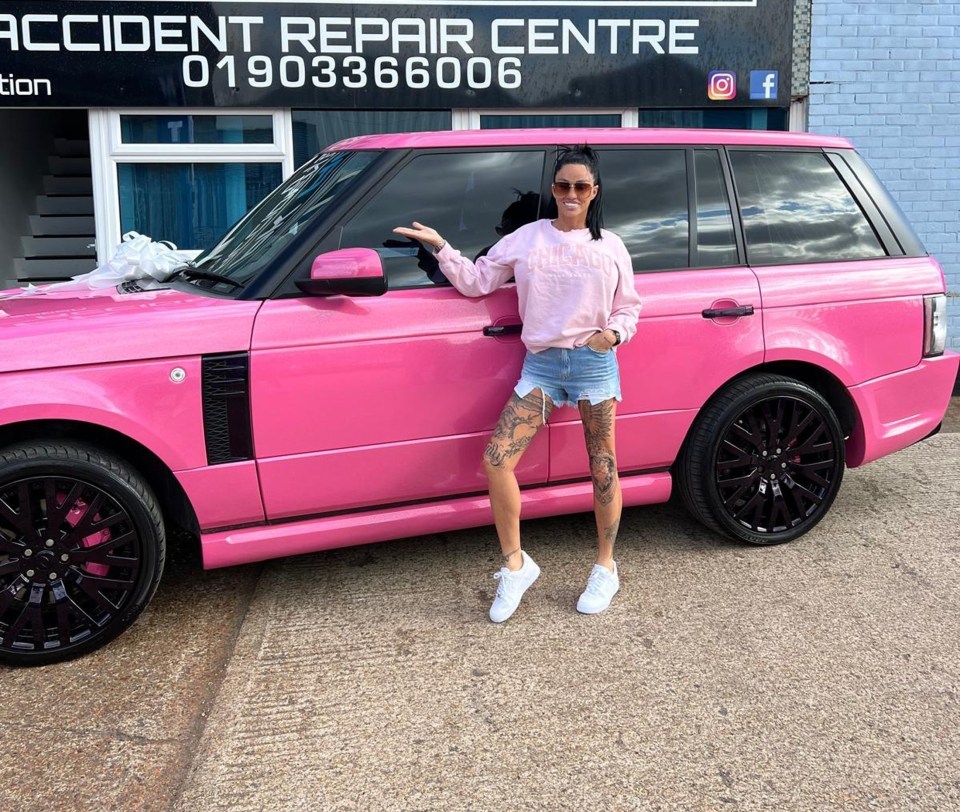 a woman stands in front of a pink range rover