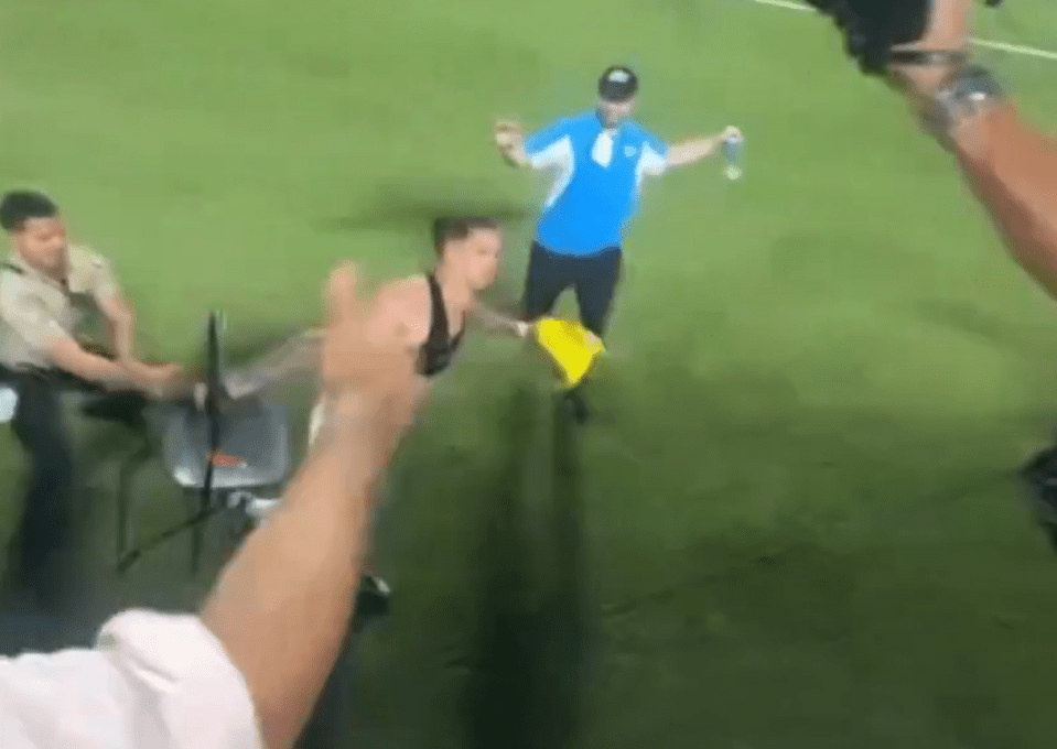 a man in a blue shirt is holding a yellow flag on a soccer field .