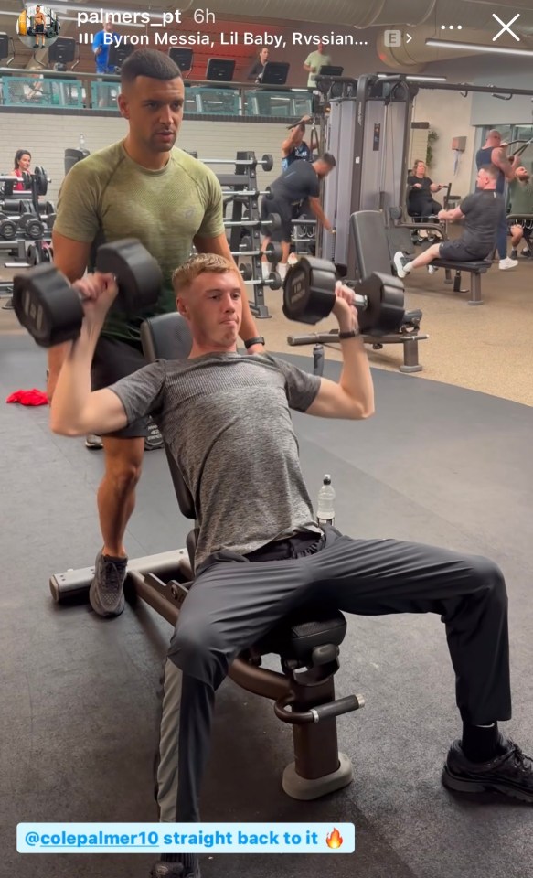 a man is lifting a dumbbell in a gym while another man watches