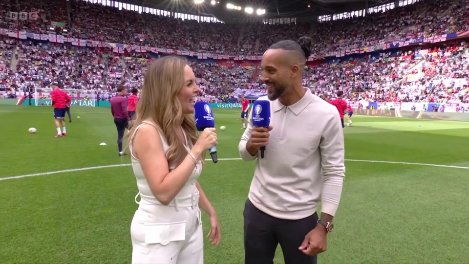 a man and a woman are talking on a soccer field with a bbc logo in the background