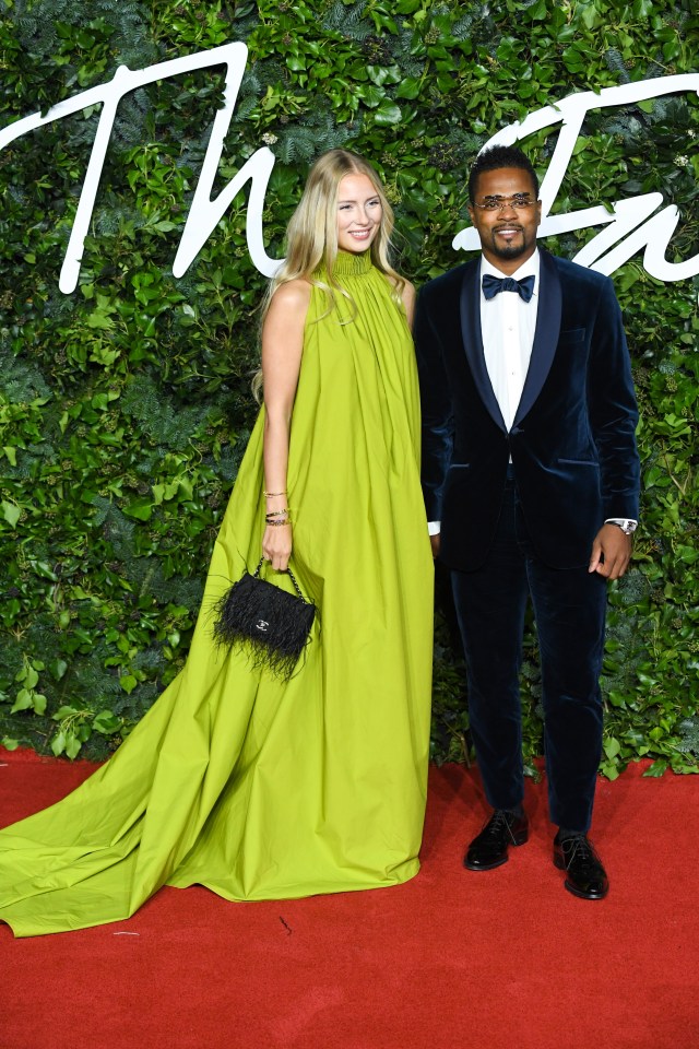 a woman in a green dress stands next to a man in a tuxedo