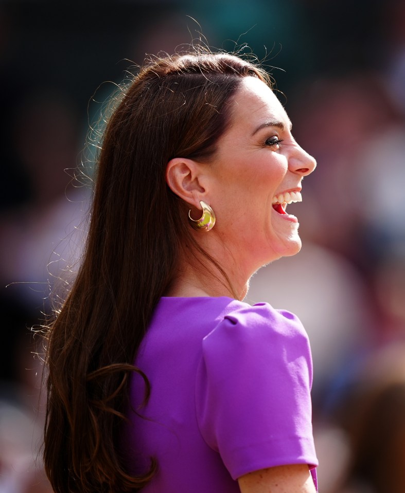 a woman in a purple shirt is laughing with her mouth open