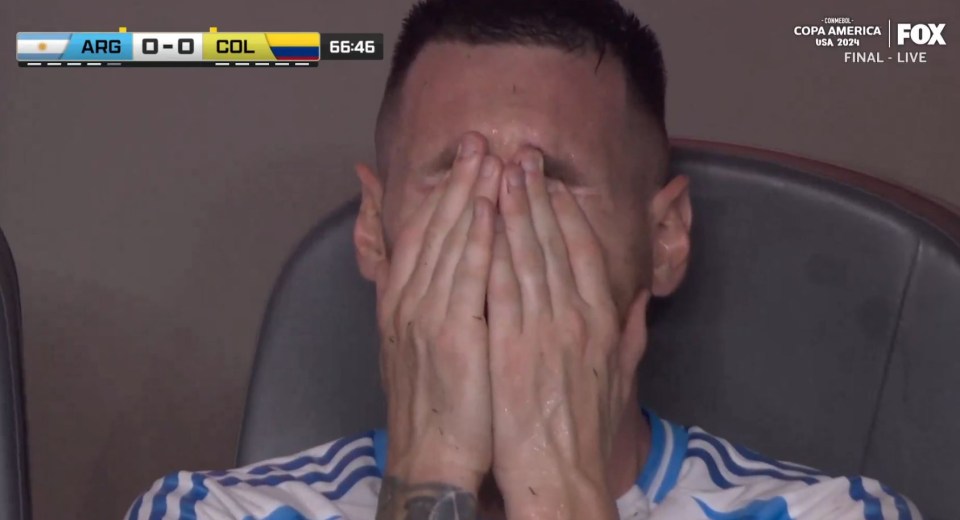 a man covering his face in front of a scoreboard that says arg 0-0 col